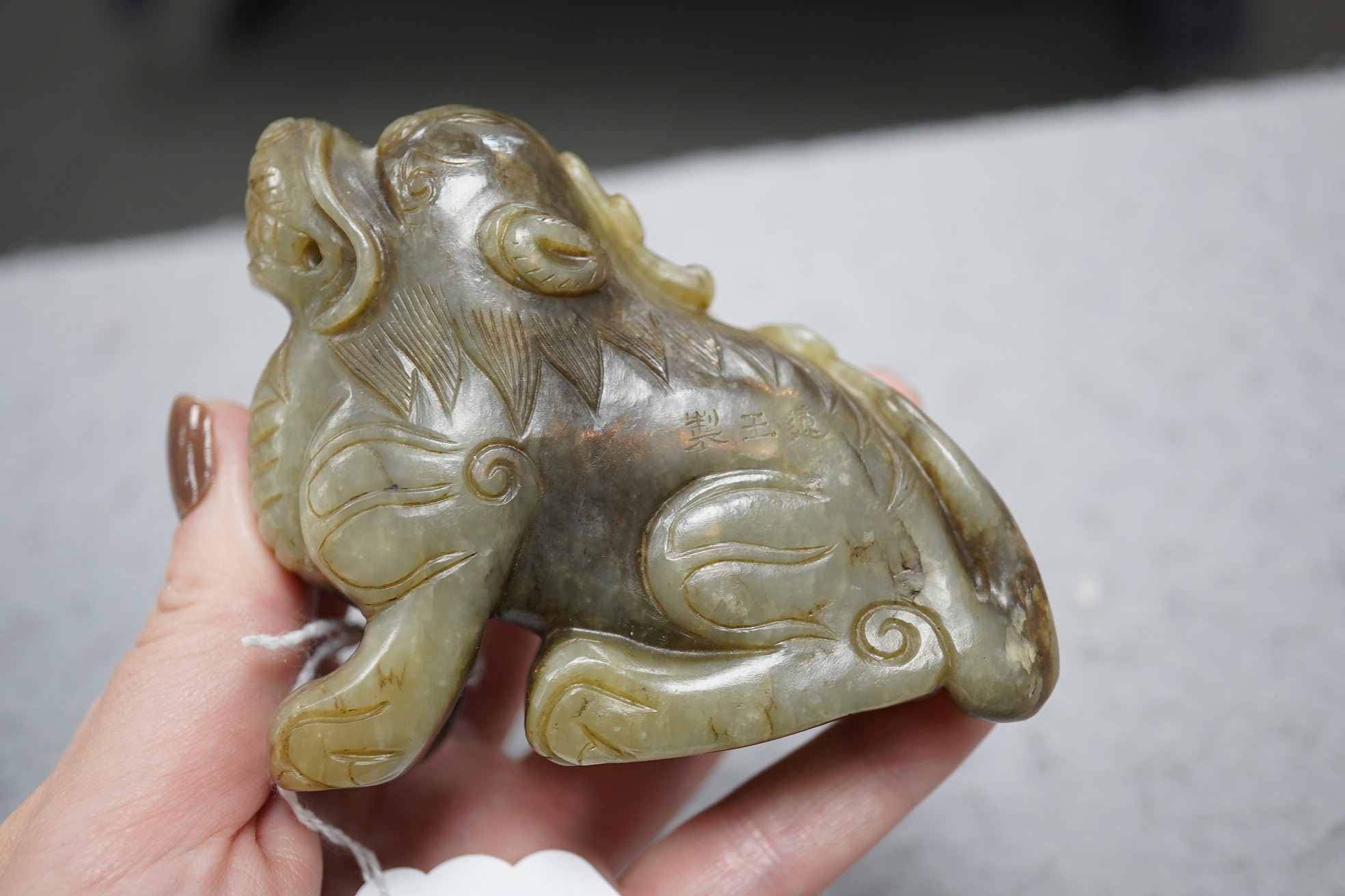 A Chinese pale grey green and black jade figure of a seated Mythical beast, Qing dynasty